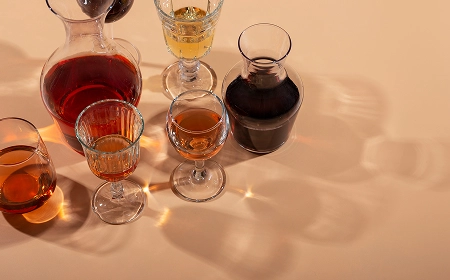 Графины и бокалы с красным, белым и янтарным алкоголем на светлом фоне